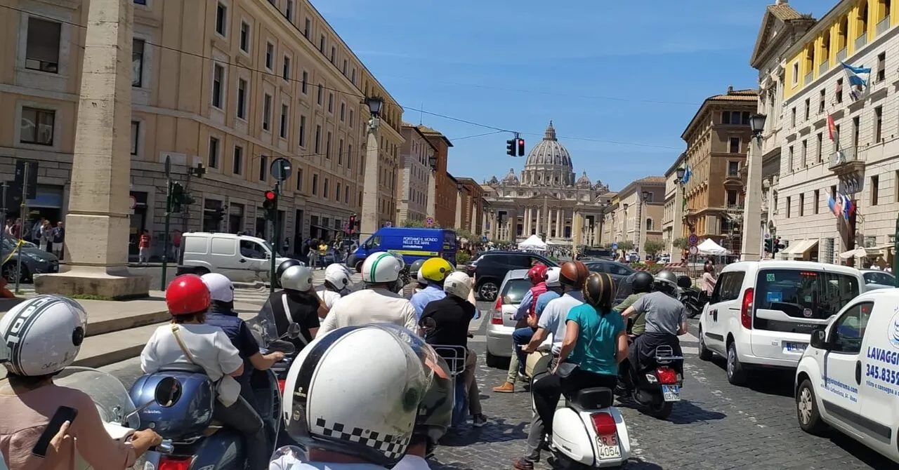 Gruppo in Vespa nel traffico del centro con la cupola di San Pietro sullo sfondo