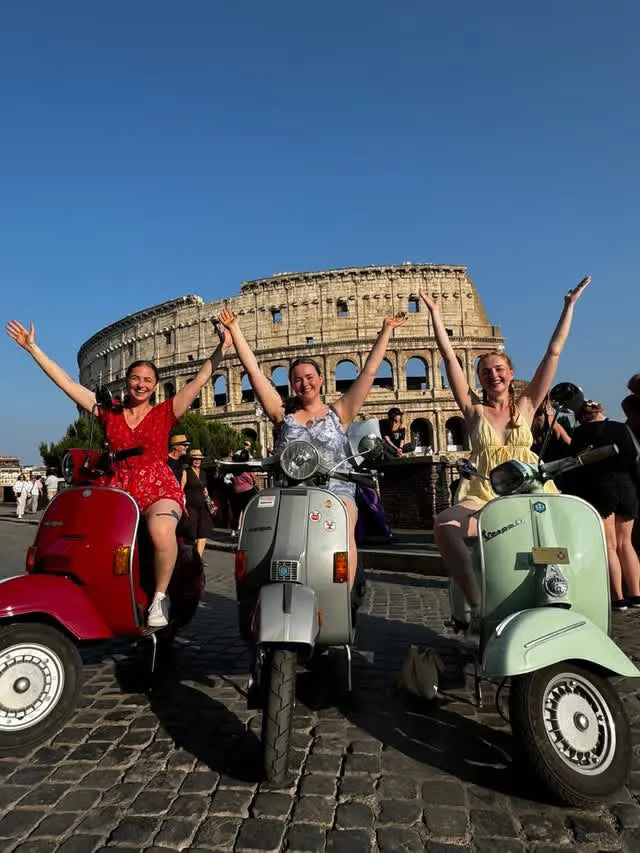 Gruppo festante in Vespa davanti al Colosseo
