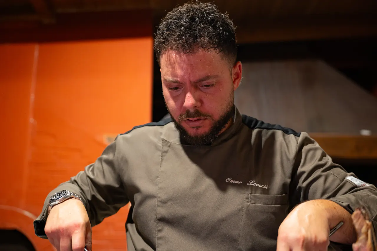 Lo chef Omar Leccesi taglia la carne alla brace durante l'evento al Tiber Village